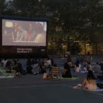 Families sit on hot concrete during Movies Under the 'Stars'/Upper East Site
