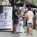 Conspiracy theorists chat with passers-by as swastika poster hangs nearby/Lance Yasinsky