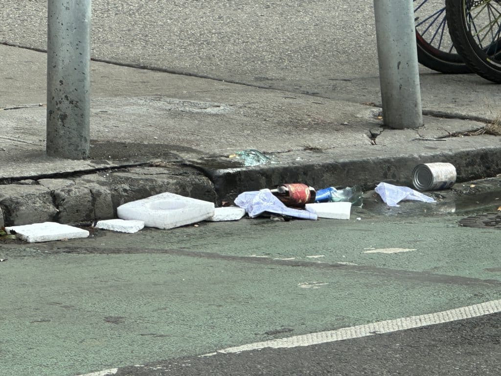 Trash accumulates along the curb of the Second Avenue bike lane | Upper East Site