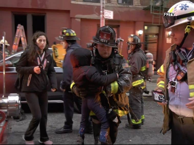 FDNY firefighter carries a child out of the burning building to safety
