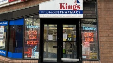 A customer reads the goodbye message posted to the doors of Kings Pharmacy | Upper East Site