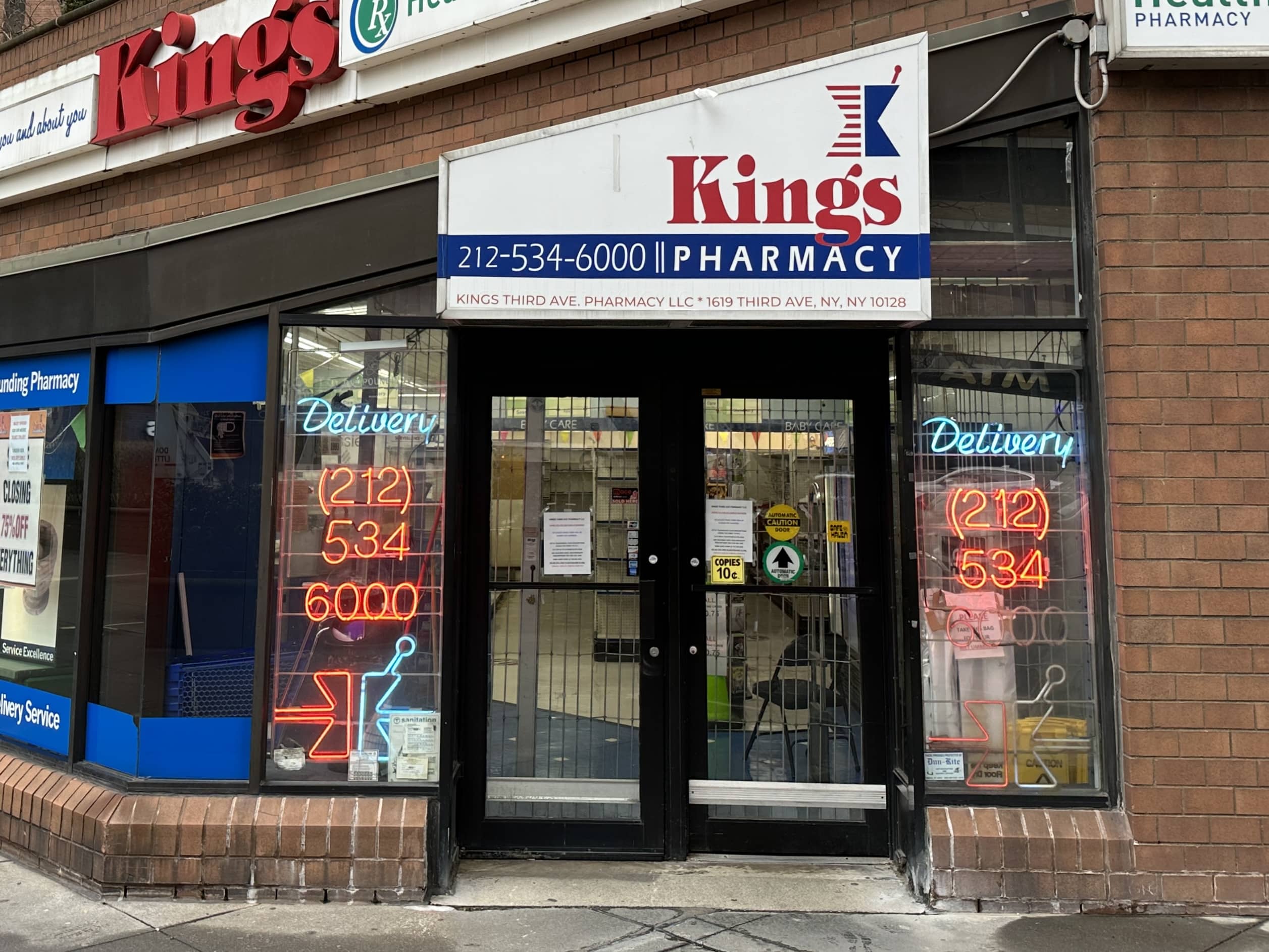 A customer reads the goodbye message posted to the doors of Kings Pharmacy | Upper East Site