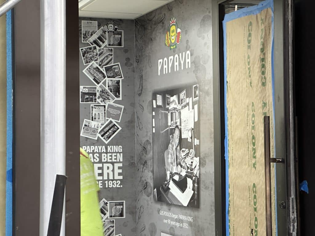 A mural by the door features photos of the original UES Papaya King | Upper East Site