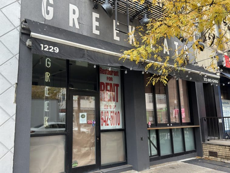 Photo shows the closed storefront of Greek Eats with its windows covered by brown paper