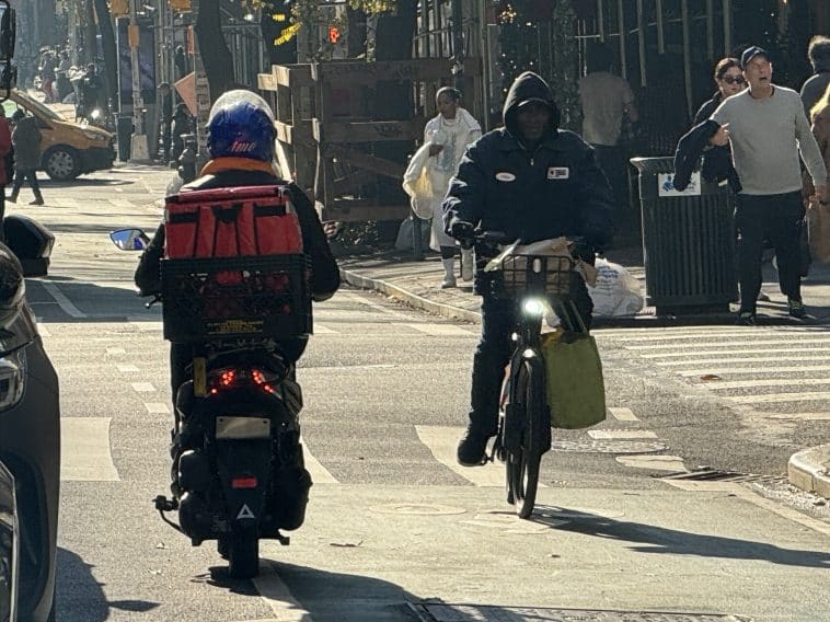 Photo shows a moped illegally riding against traffic in the Third Avenue bike lane as a speeding e-bike navigates past