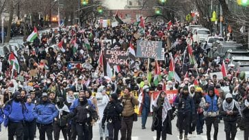 Photo shows a crowd of more than 1,000 people walking toward the camera, lead by police.