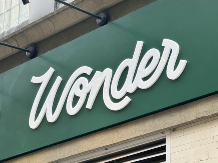 Photo shows a green sign featuring white writing reading 'Wonder.'