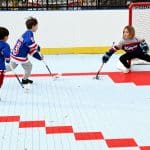 Photo shows three children in Rangers gear playing ball hockey on a newly renovated court.