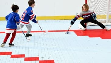 Photo shows three children in Rangers gear playing ball hockey on a newly renovated court.