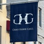 Photo shows a large navy blue banner with the 'Gray Hawk Grill' logo and name printed in the center.