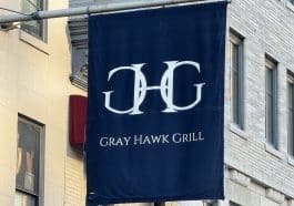 Photo shows a large navy blue banner with the 'Gray Hawk Grill' logo and name printed in the center.