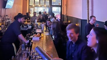 Photo shows the interior of a small cocktail bar busy with guests.