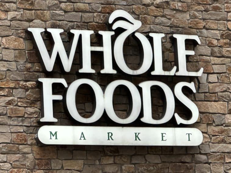 Photo shows a brick wall with a white sign for Whole Foods Market.