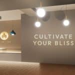 Rendering shows the interior of a dispensary in neutral tones with 'CULTIVATE YOUR BLISS' written on a wall.