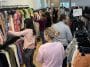 Photo shows several people shopping for clothes on racks inside a large retailer.