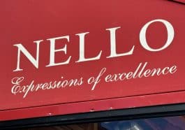 Photo shows a red awning with a restaurant name, 'Nello, and slogan, 'Expressions of Excellence,' written in white.