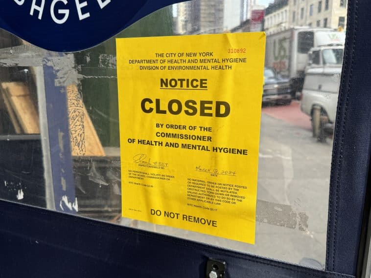 Photo shows a yellow Health Department closure notice on a door.