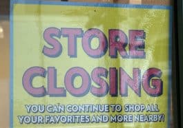 Photo shows a yellow sign in a store window reading 'STORE CLOSING.'