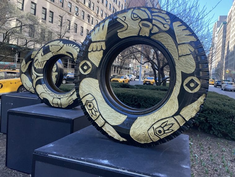 Photo shows three recycled tires with artwork carved into them.