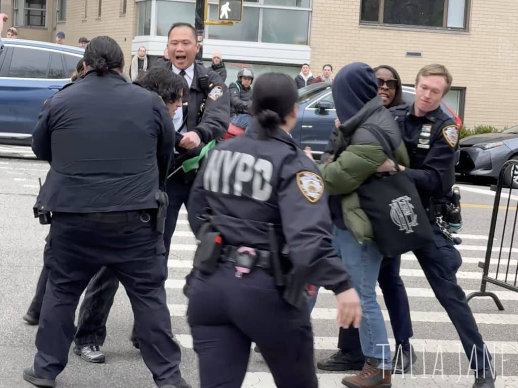 Photo shows police arresting protesters.