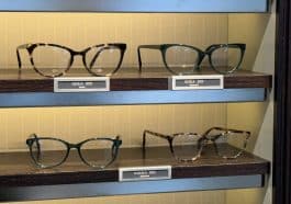 Photo shows eyeglasses on a shelf.