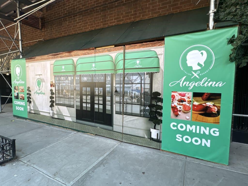 Photo shows a storefront under construction with a large banner featuring a rendering of a finished storefront on it.