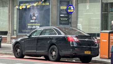 Photos shows a black armored NYPD Ford Taurus parked in front of a newsstand.