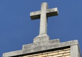 Photo shows a stone crucifix atop a rectory building.
