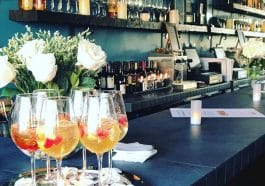Photo shows a long dark bar with glasses of sangria on the counter.